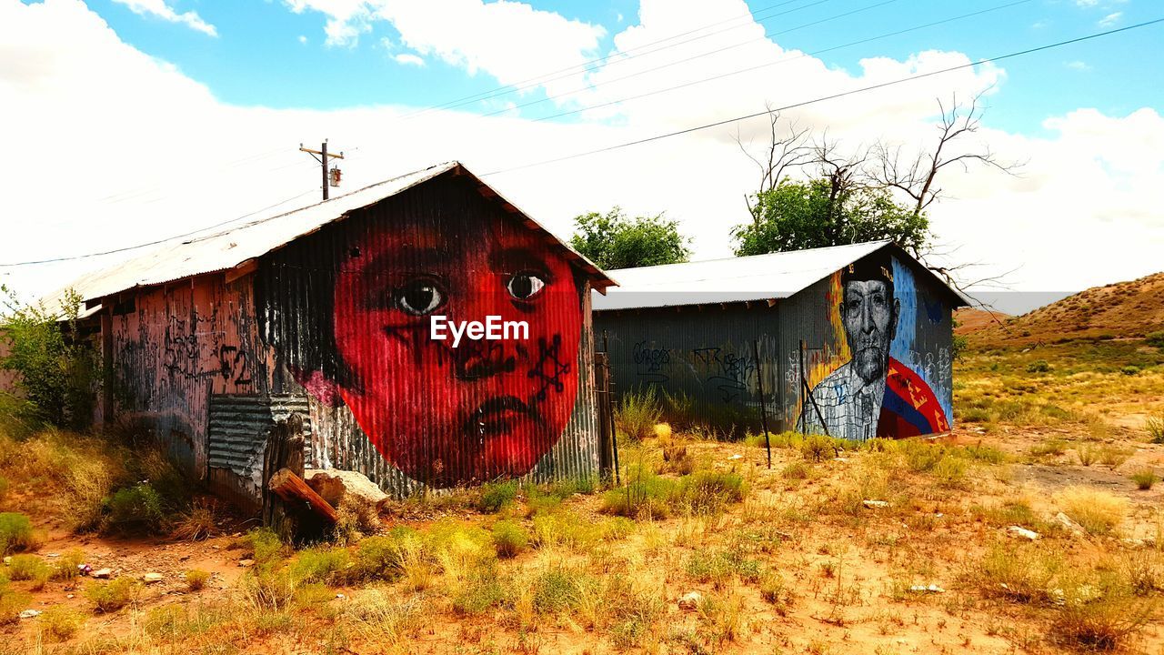 Graffiti on abandoned huts against sky