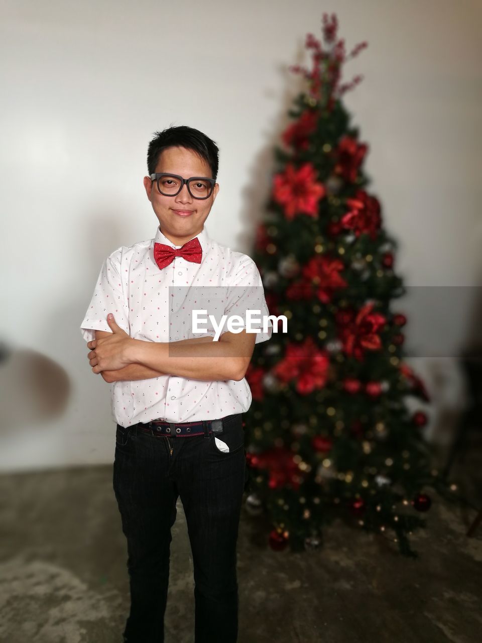 Portrait of smiling young man standing by christmas tree at home