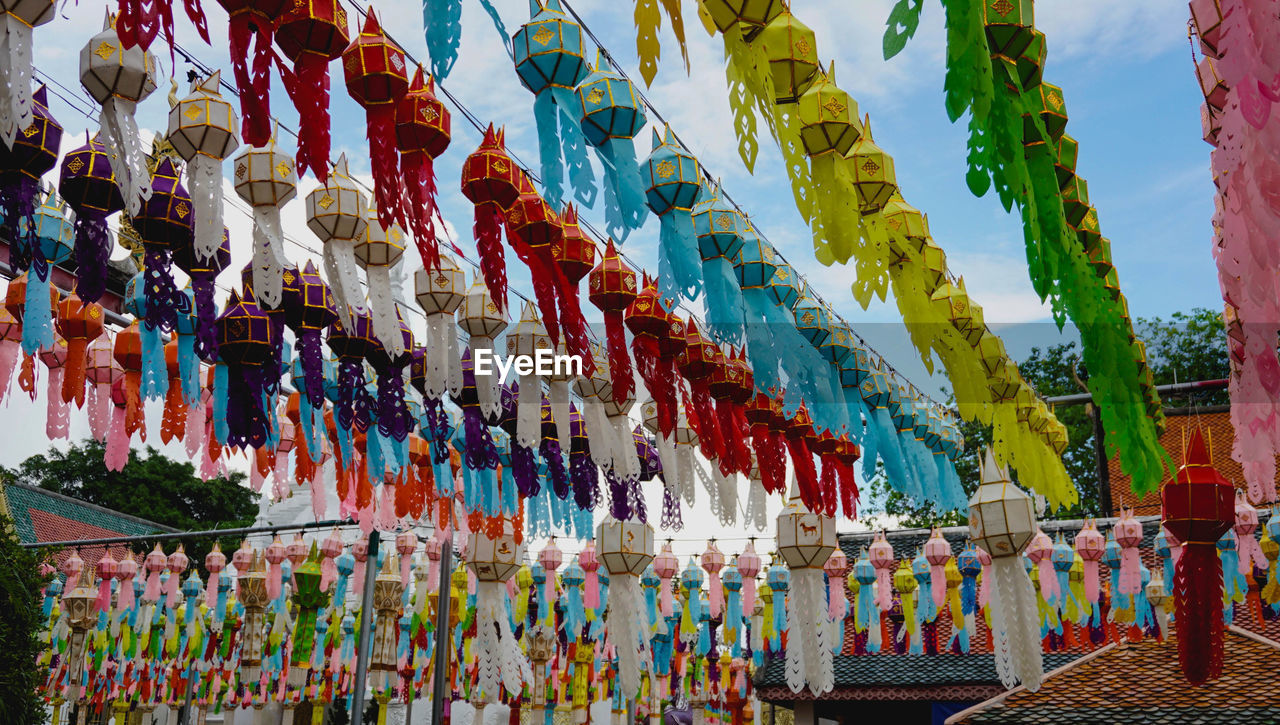 LOW ANGLE VIEW OF DECORATIONS HANGING AMIDST BUILDINGS