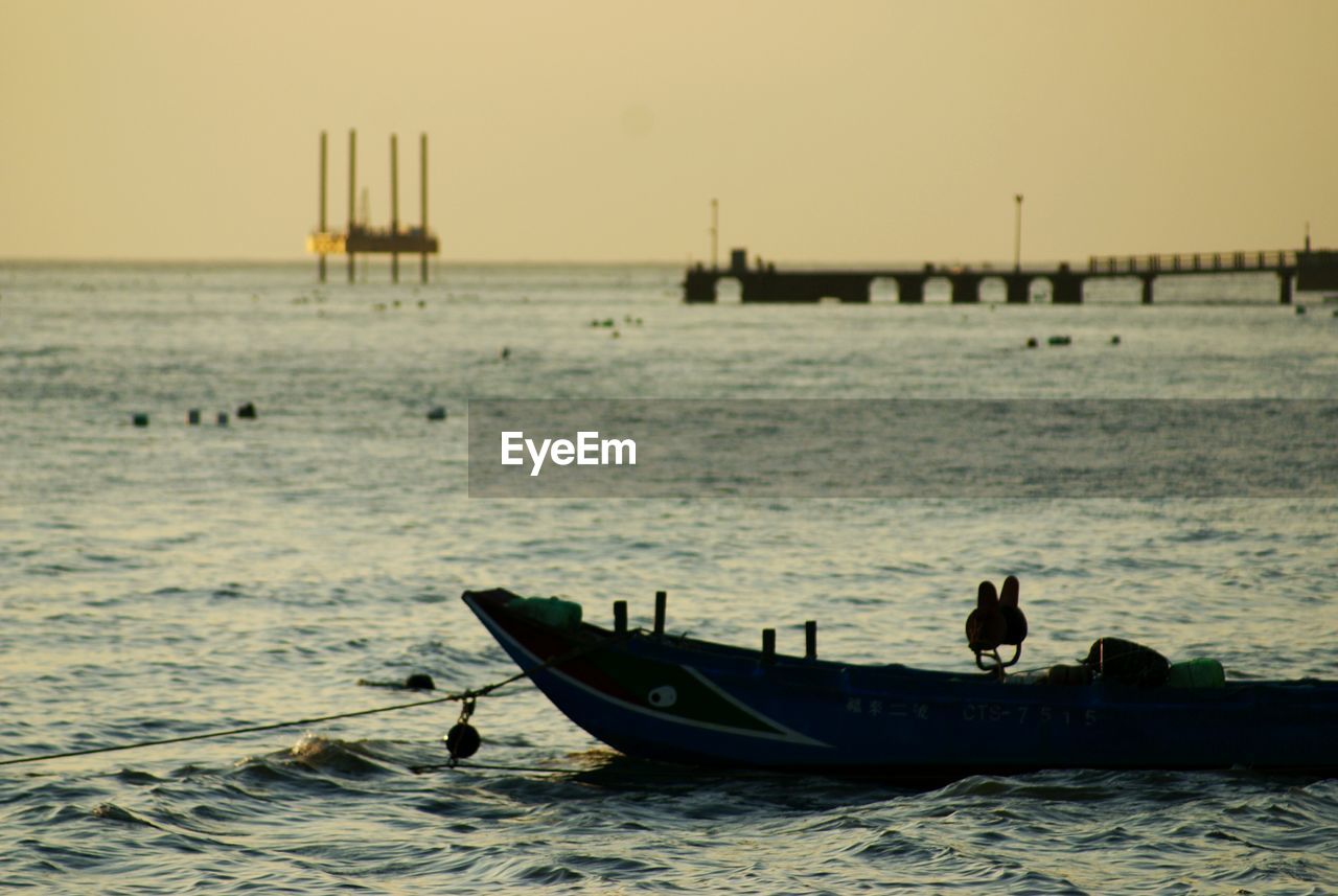 Boat moored on sea against clear sky during sunset