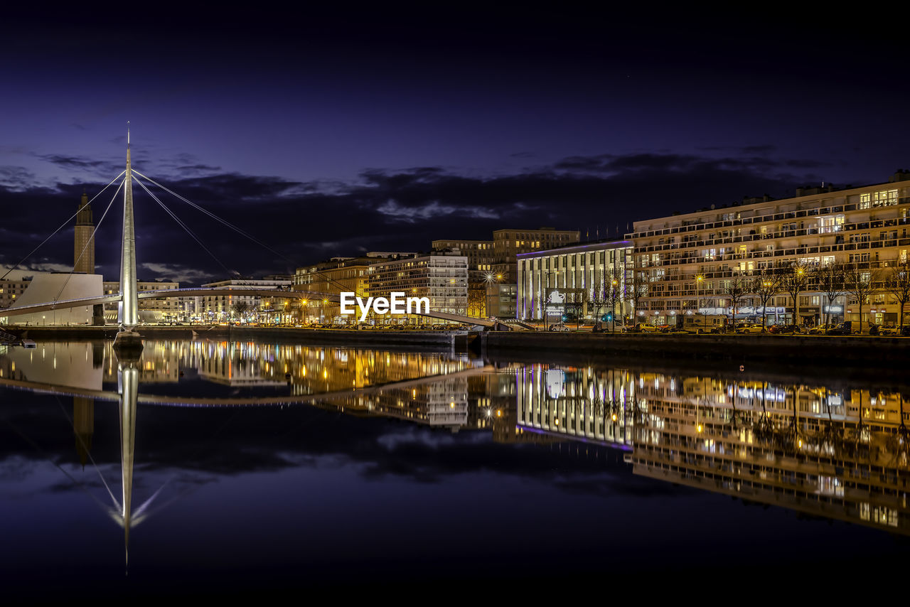 Reflection of illuminated bridge over river against sky at night