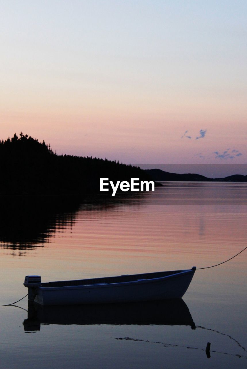 Nautical vessel moored in lake during sunset