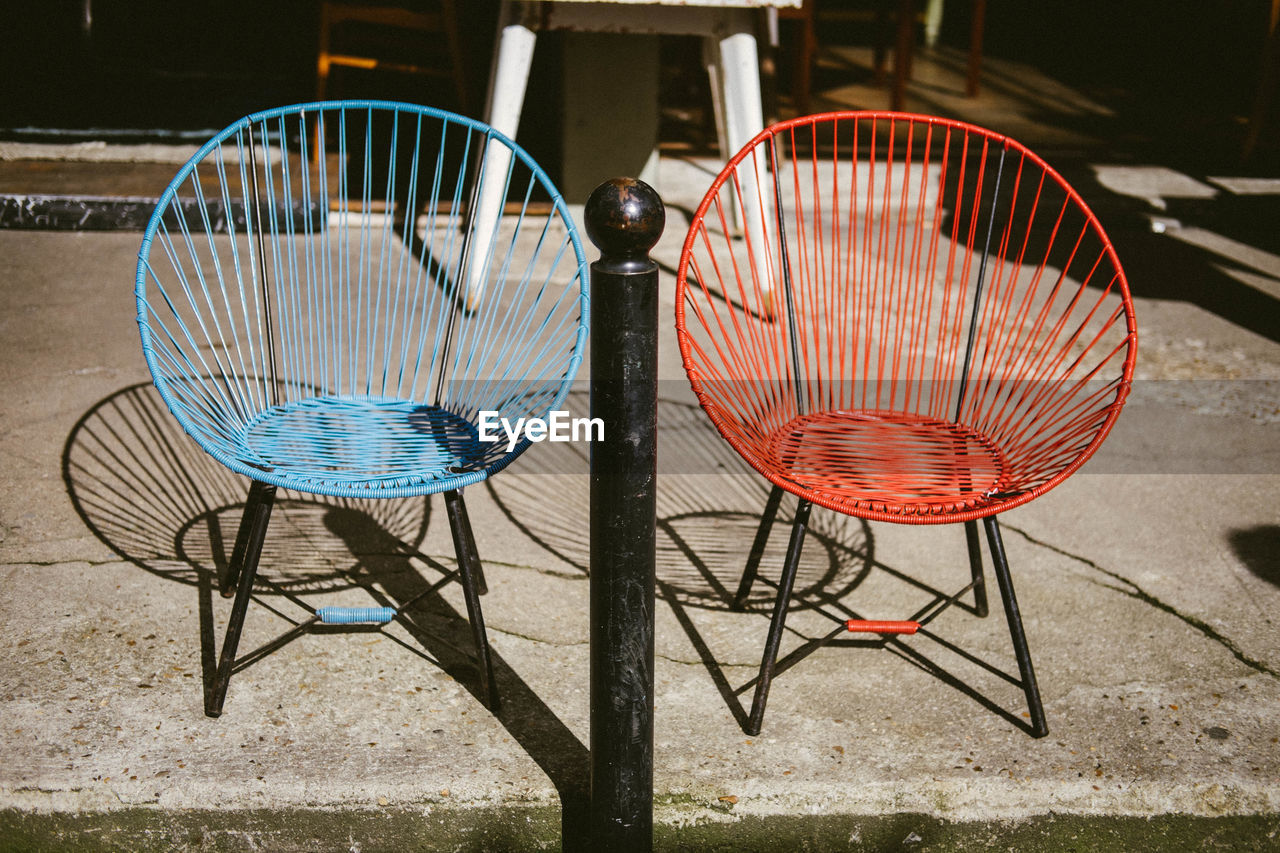 EMPTY CHAIRS AND TABLE BY SIDEWALK CAFE