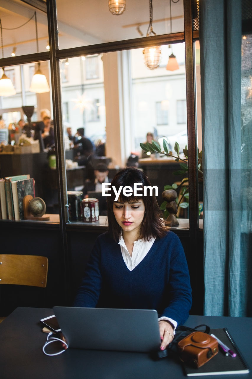 Confident businesswoman using laptop at desk in creative office