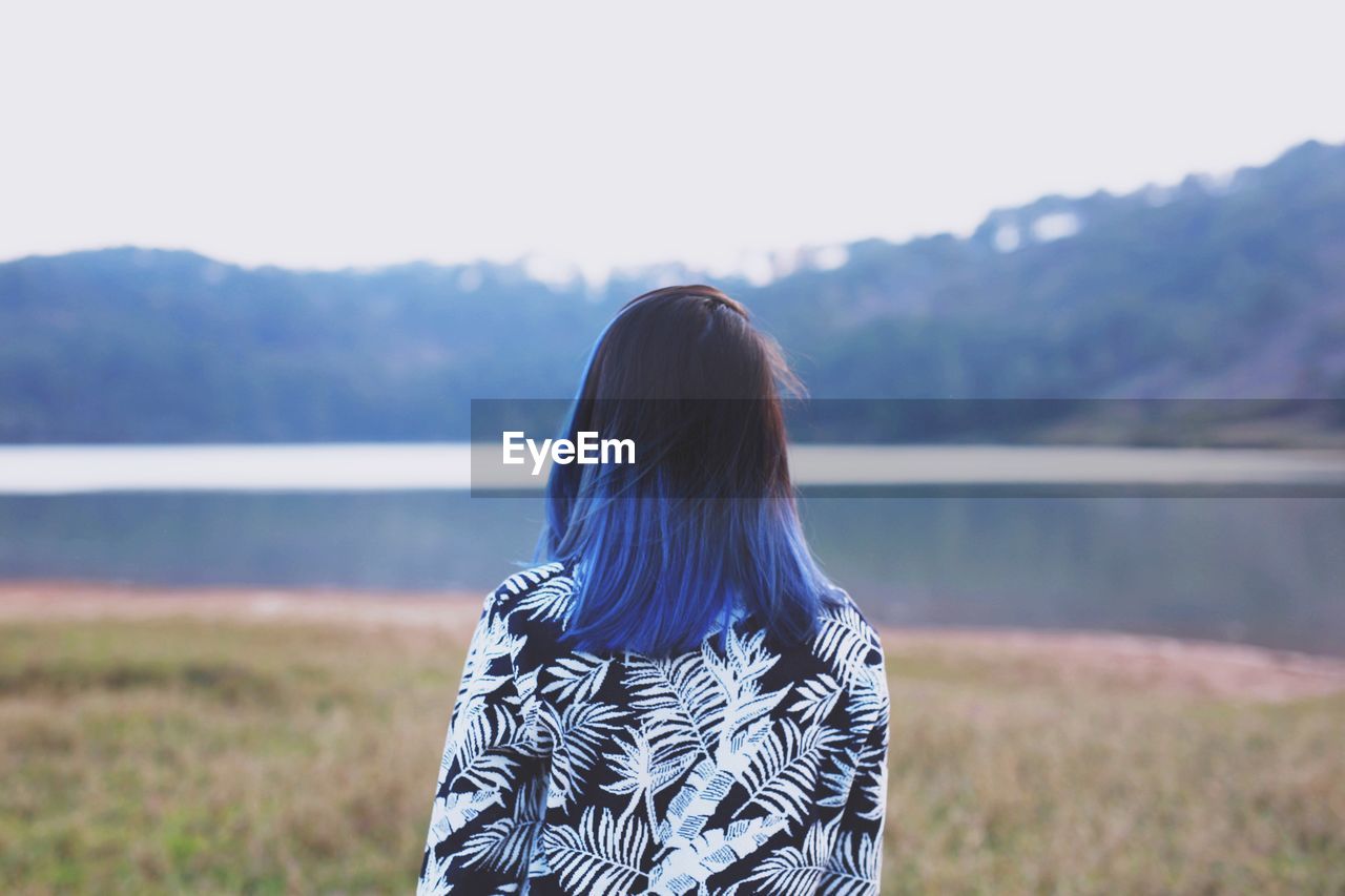 Rear view of woman standing in front of river