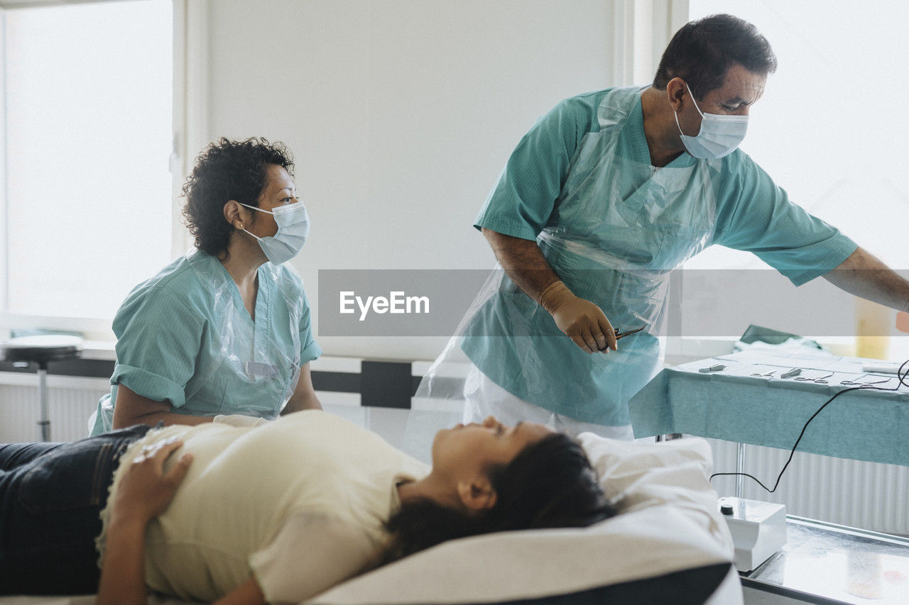 Surgeons in masks examining female patient in hospital