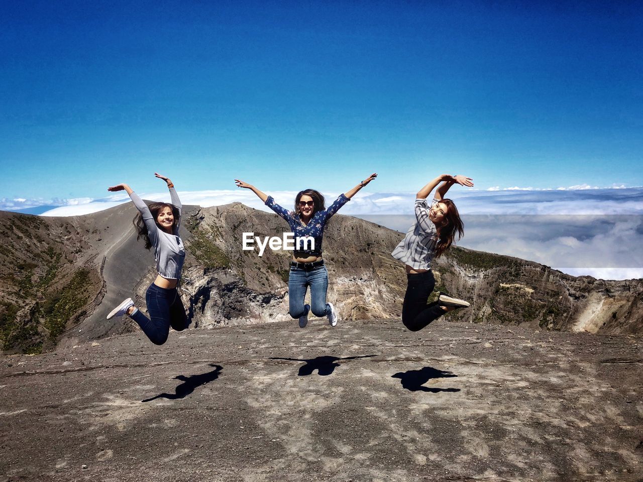 Friends jumping against sky