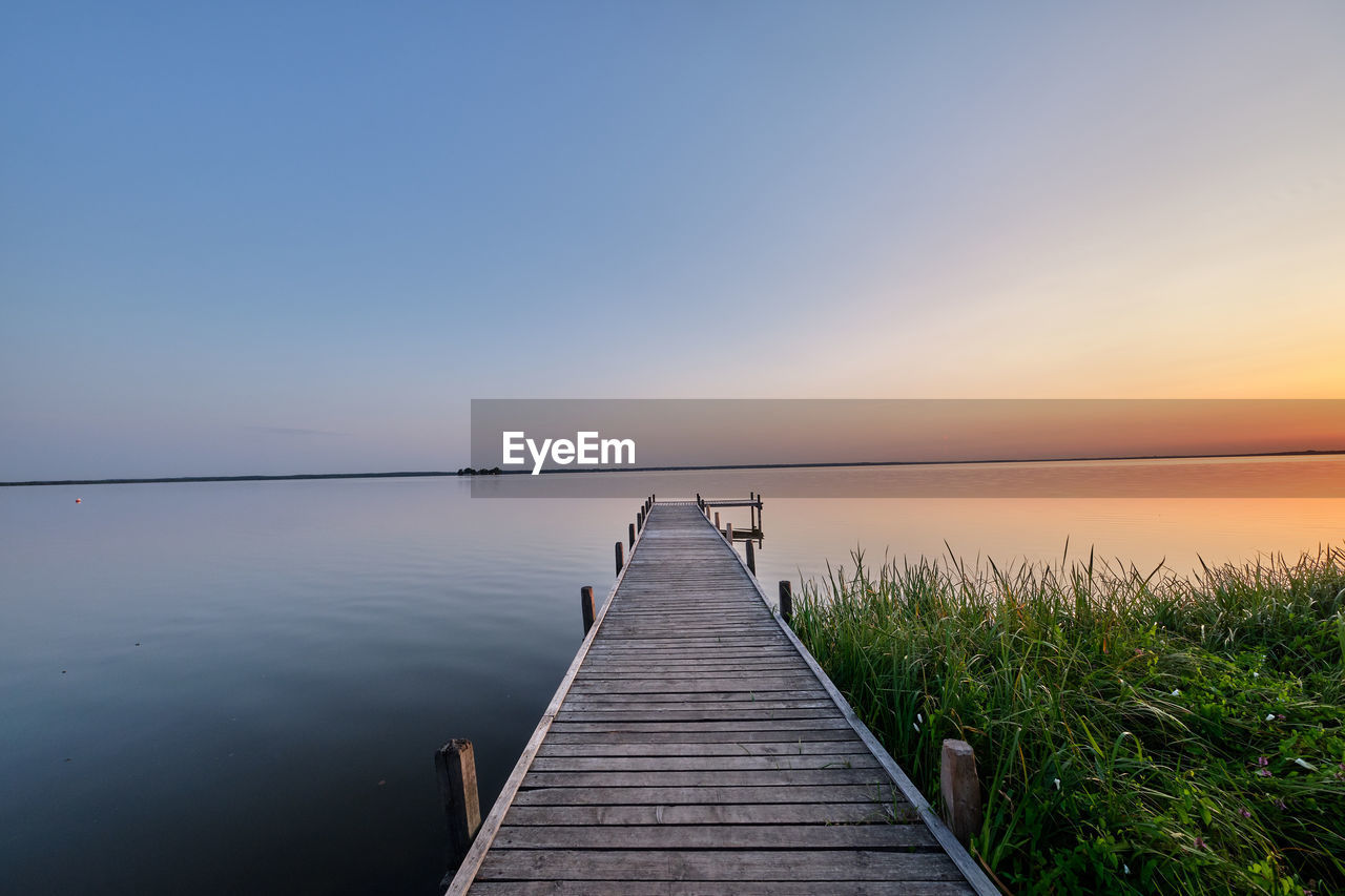 Pier over lake against clear sky during sunset