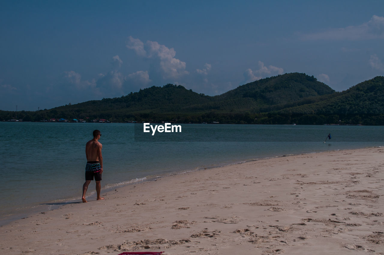 WOMAN ON BEACH AGAINST SKY