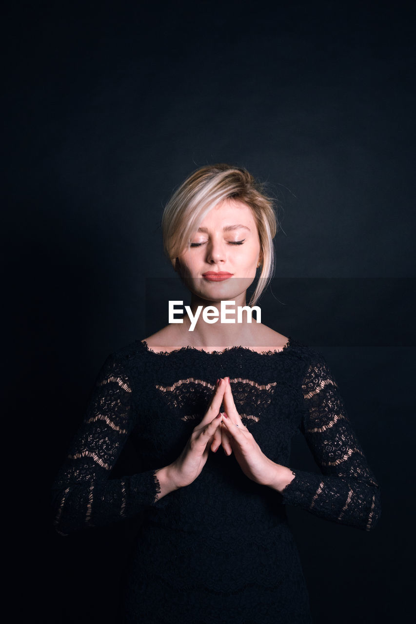 Woman praying against black background