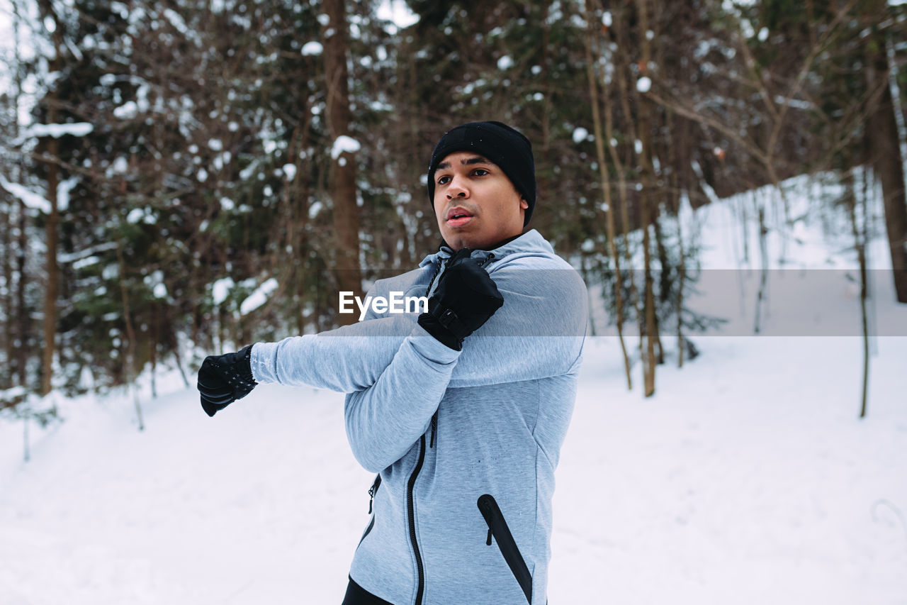 Young man exercising while wearing warm clothing during winter