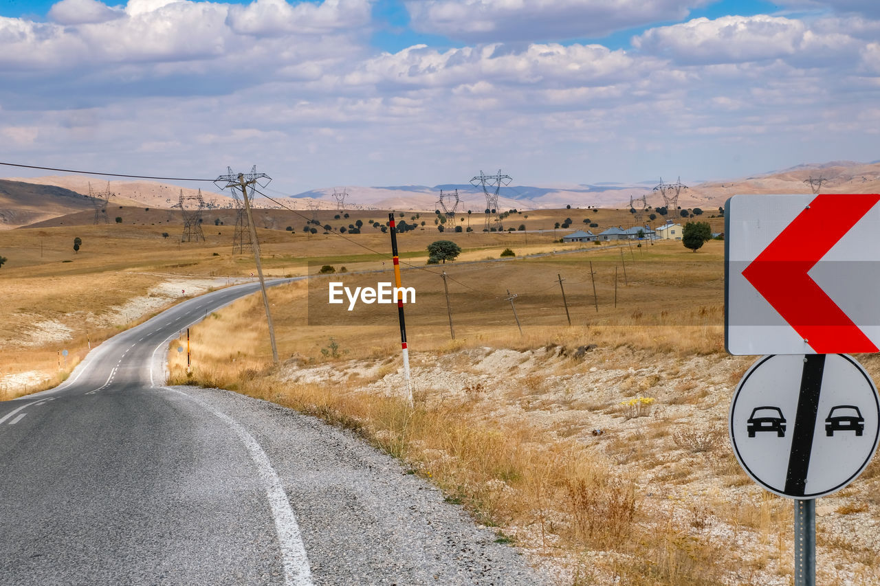 Road sign on field against sky