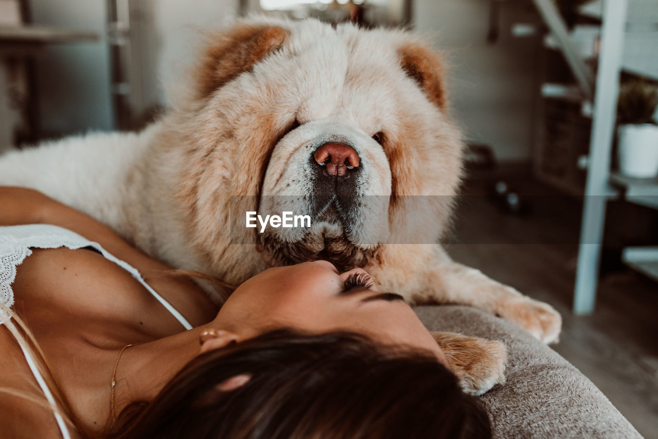 Young woman with dog lying on bed at home