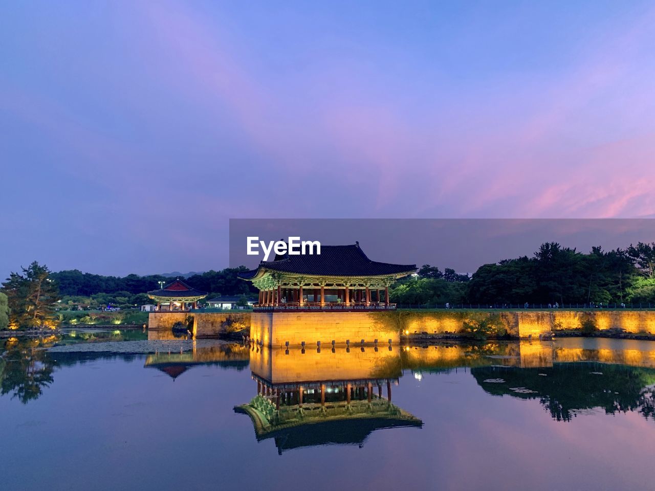 BUILDING BY LAKE AGAINST SKY DURING SUNSET