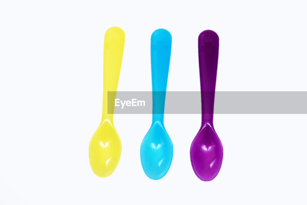 Directly above multi colored plastic spoons against white background