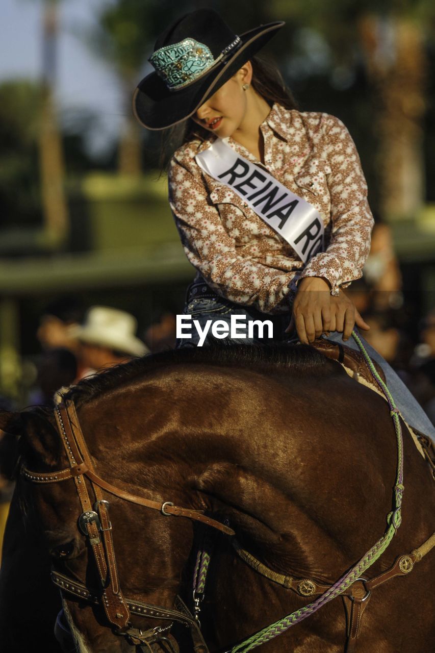 MIDSECTION OF WOMAN RIDING HAT