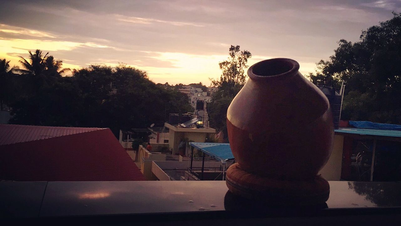 CLOSE-UP OF STATUE AGAINST CITYSCAPE DURING SUNSET