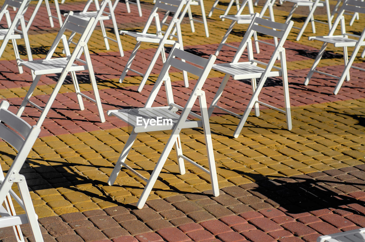 Folding chairs are arranged on recreation area. empty folding wooden chairs in a public square