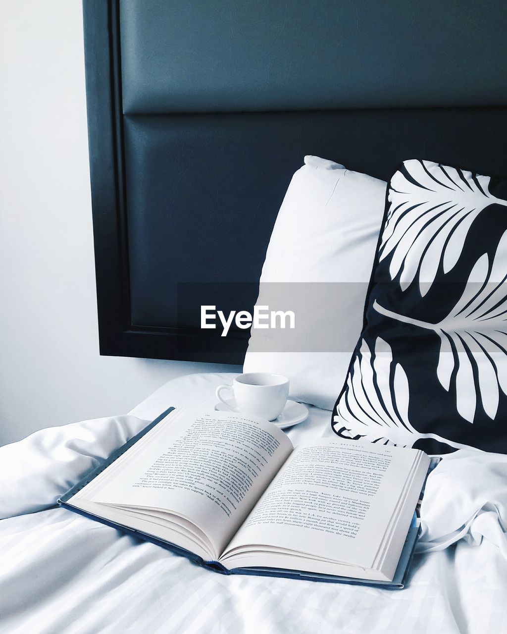 High angle view of book with cup and cushions on bed