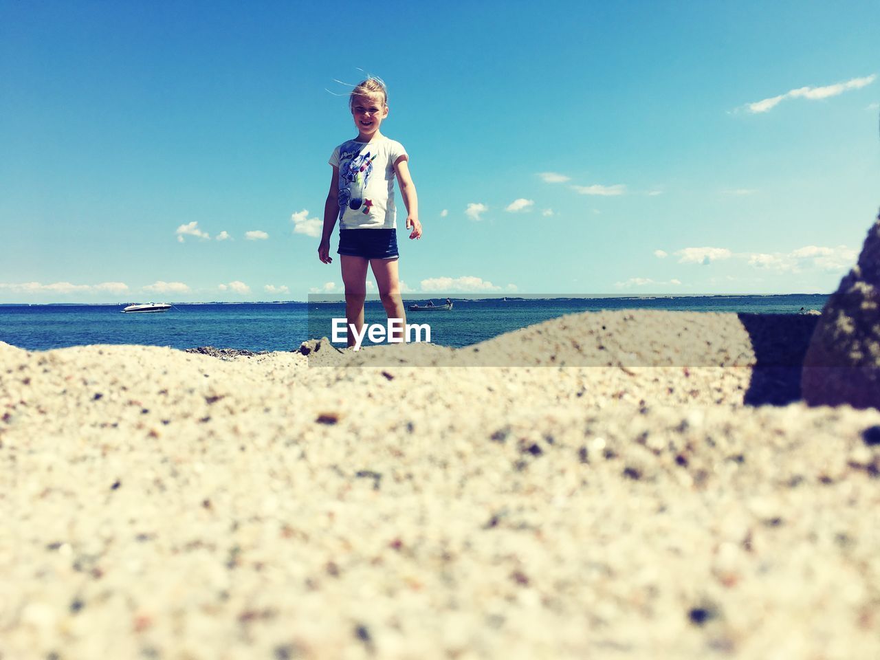 Portrait of girl standing at beach against sky