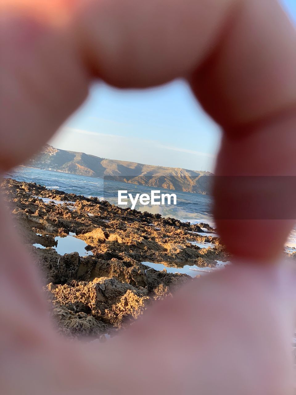 Cropped image of hand against sea