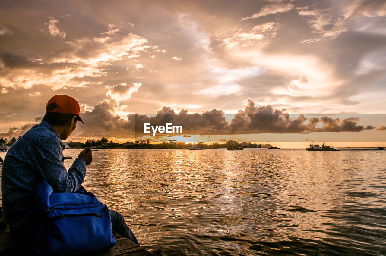 MIDSECTION OF MAN IN LAKE AGAINST SKY