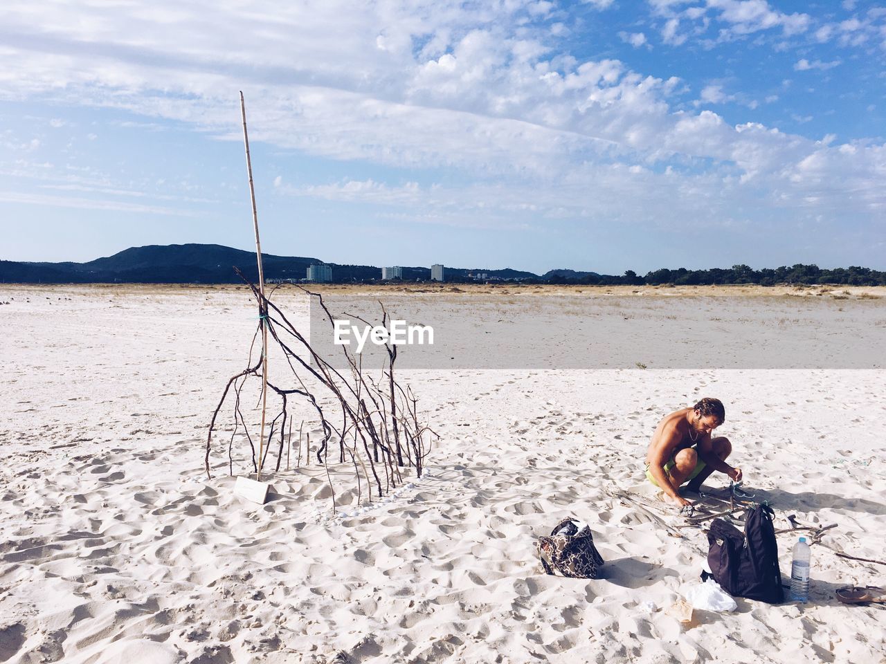 MAN IN SAND AT BEACH AGAINST SKY