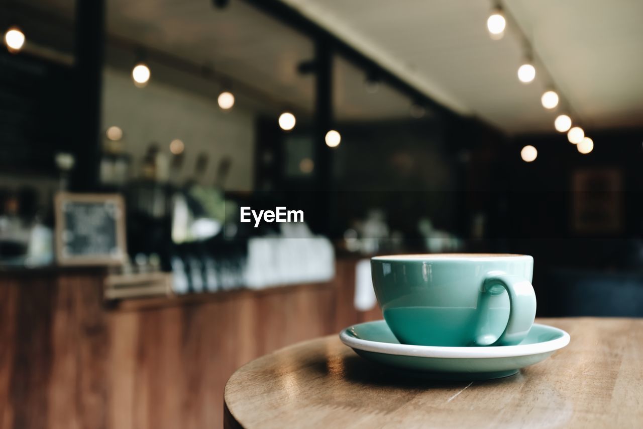 Close up view of a green coffee mug on table wooden in a coffee shop