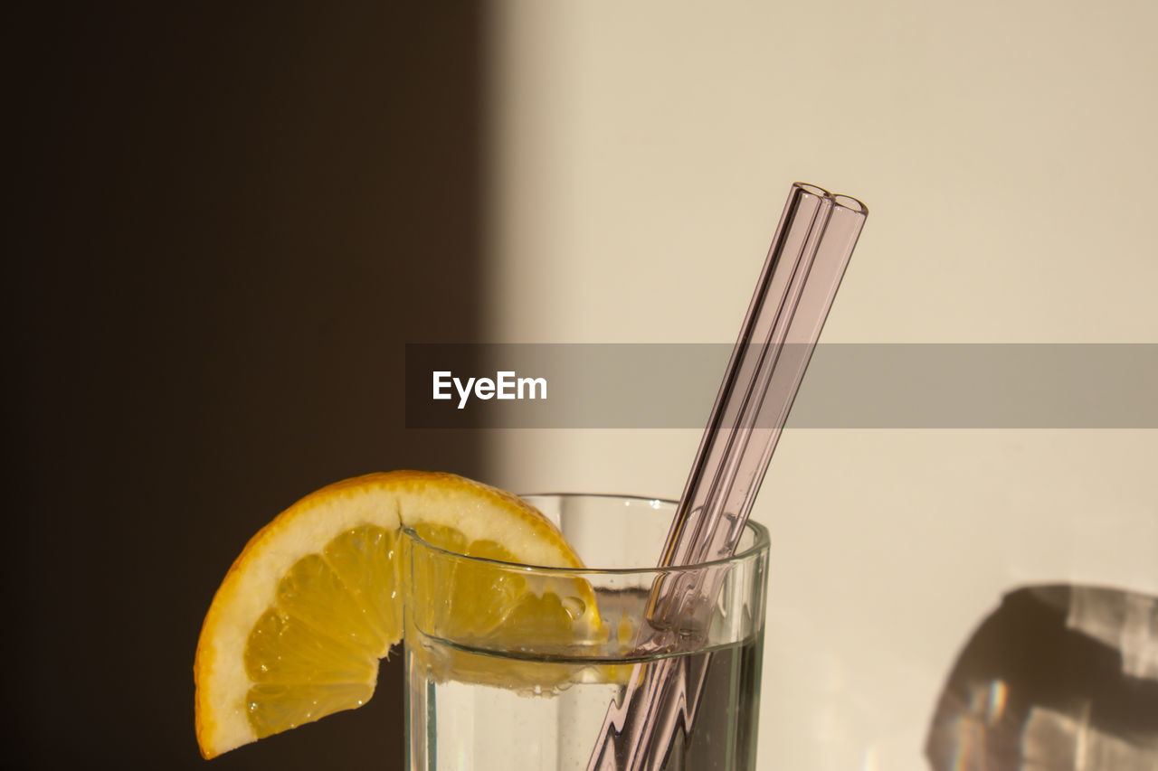 Glass of water with fresh lemon juice with reusable glass straws detox cold tonic water with sunny