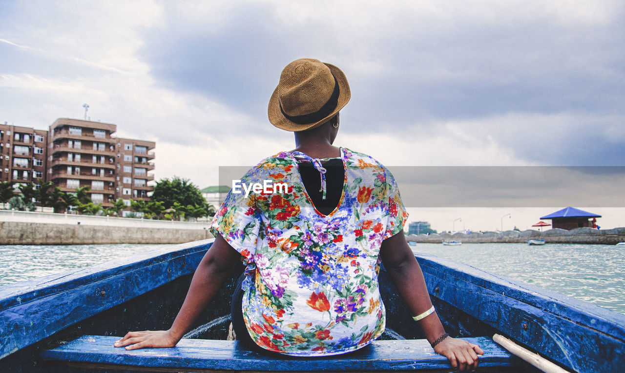 Woman sitting in boat on lake against sky