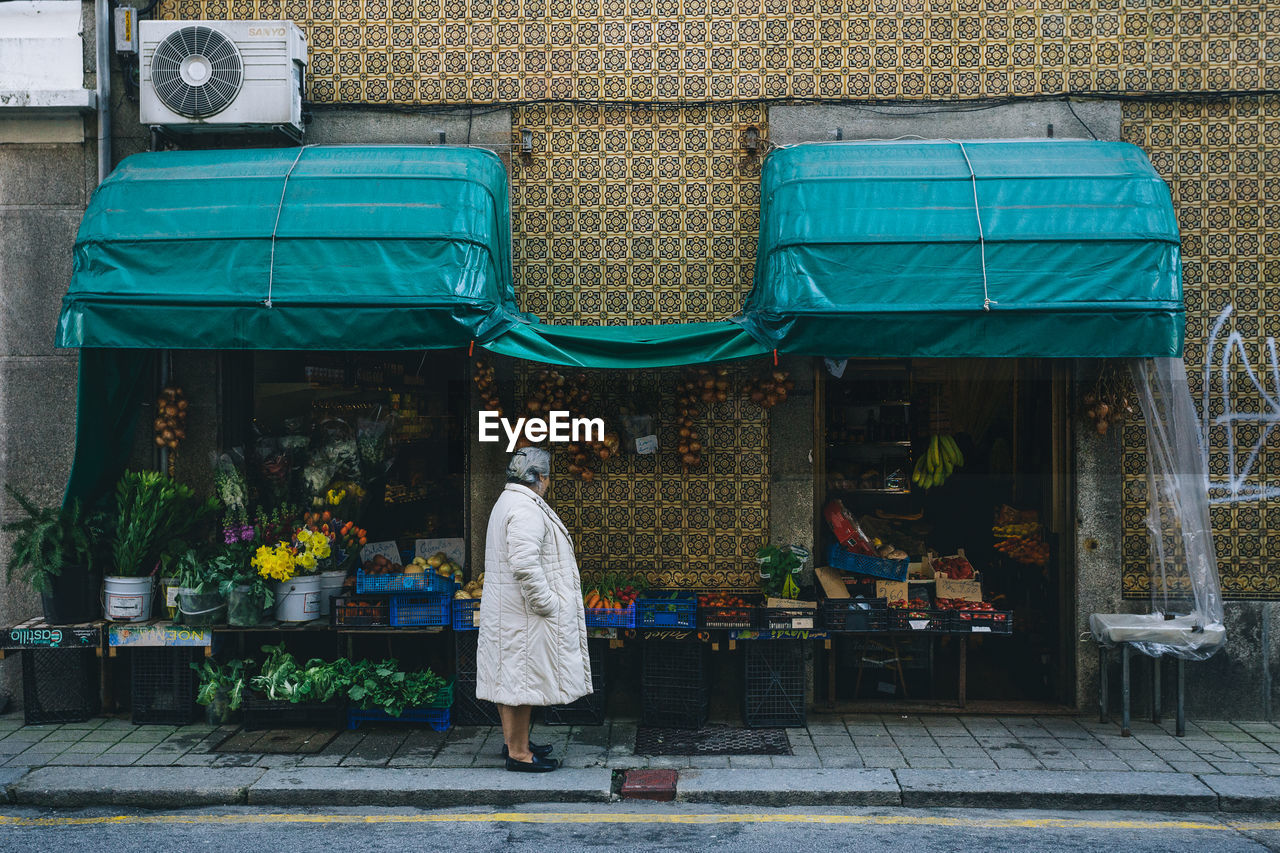 REAR VIEW OF WOMAN WITH UMBRELLA WALKING IN FLOWER