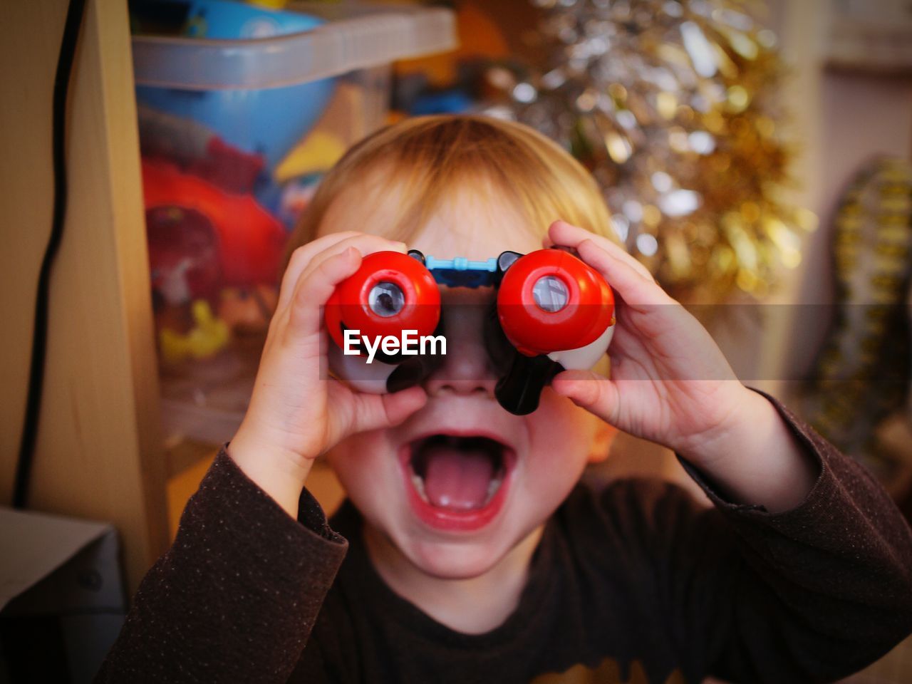 Close up of boy looking through binoculars at home