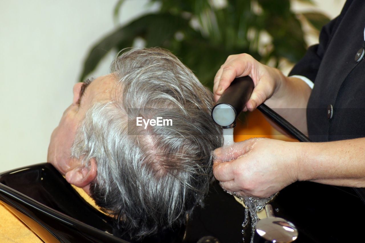 Close-up of man getting hair washed at salon