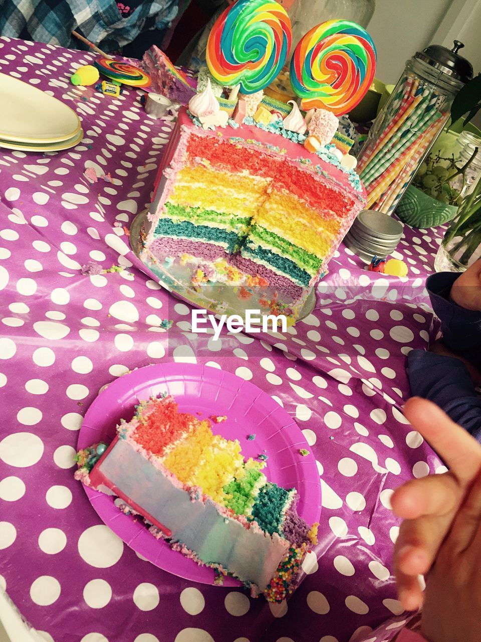 Cropped image of people having rainbow cake on table