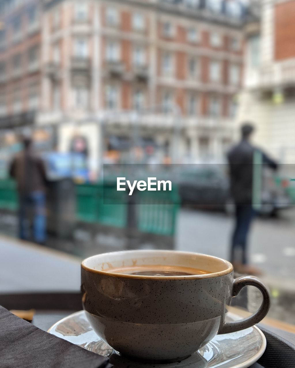 Close-up of coffee on table against buildings in city