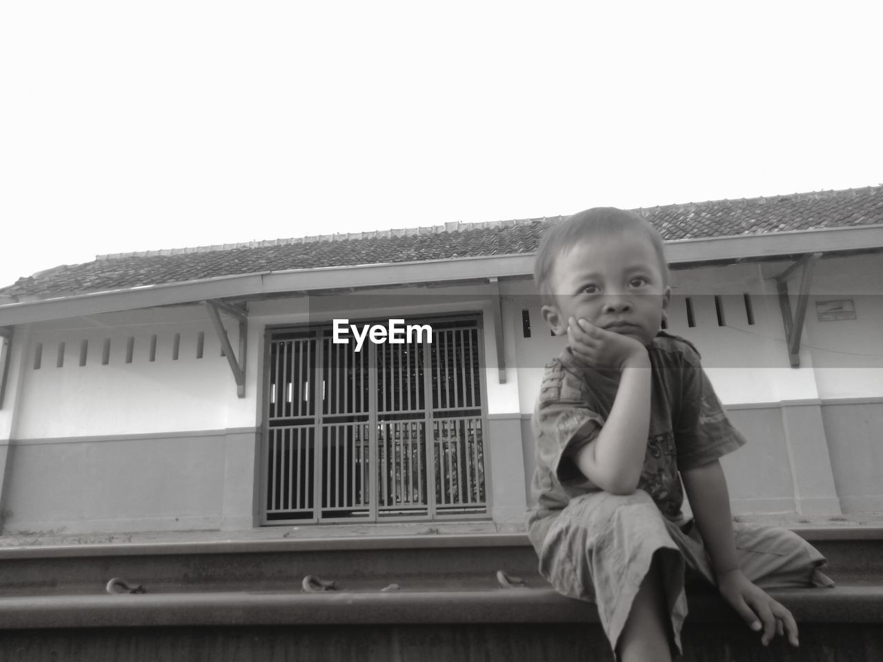 FULL LENGTH PORTRAIT OF BOY SITTING AGAINST CLEAR SKY