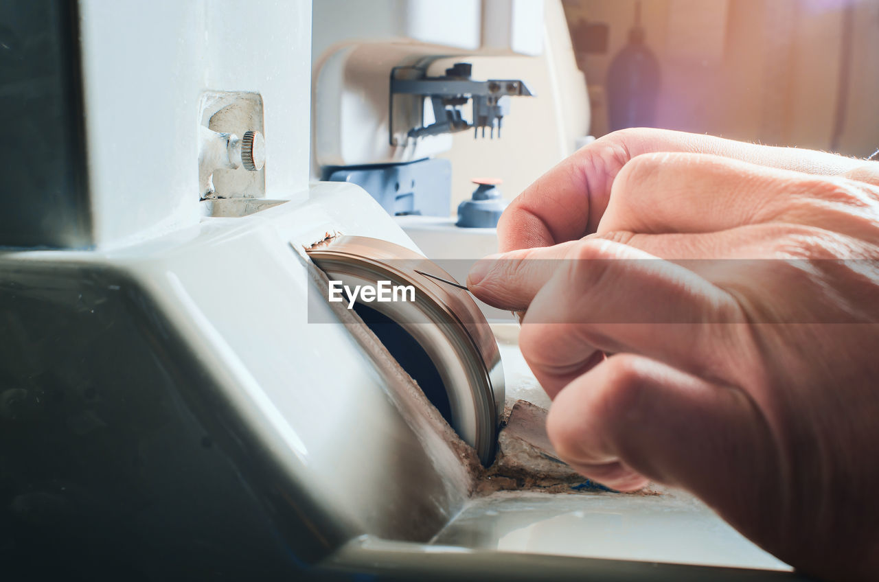 Hands of a man sharpening a needle on a grinding wheel