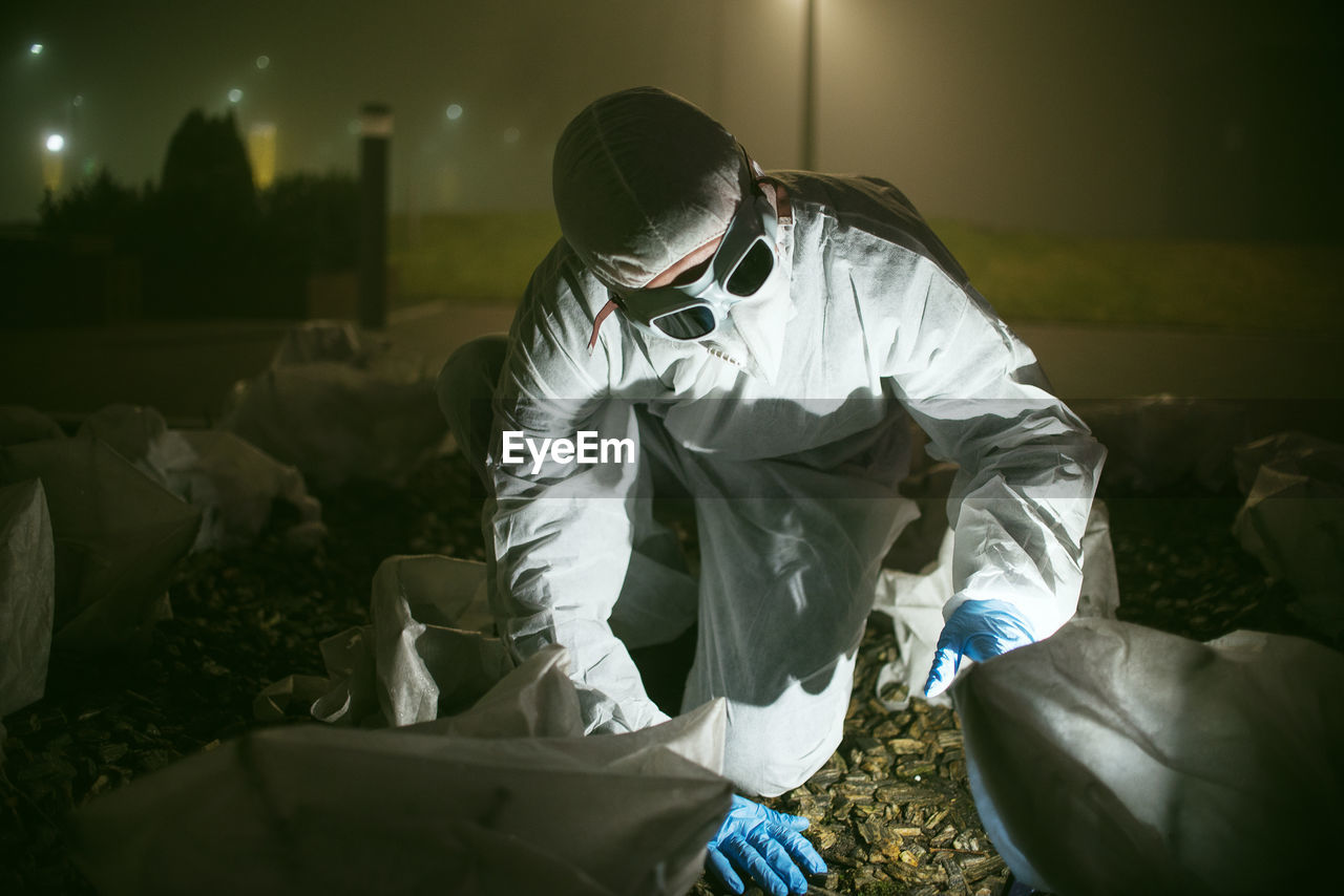 Scientist wearing protective workwear working outdoors at night