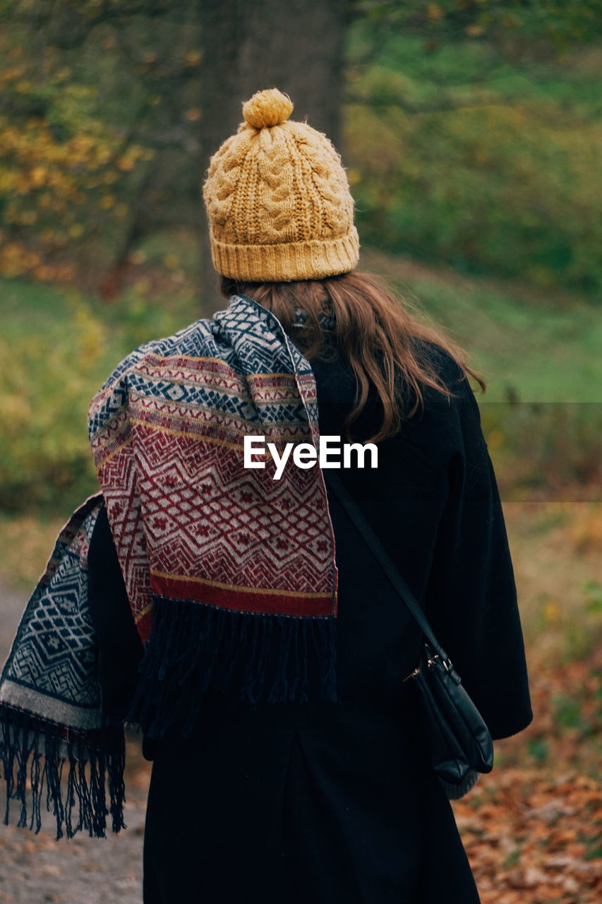 Rear view of woman wearing warm clothing standing in park during autumn