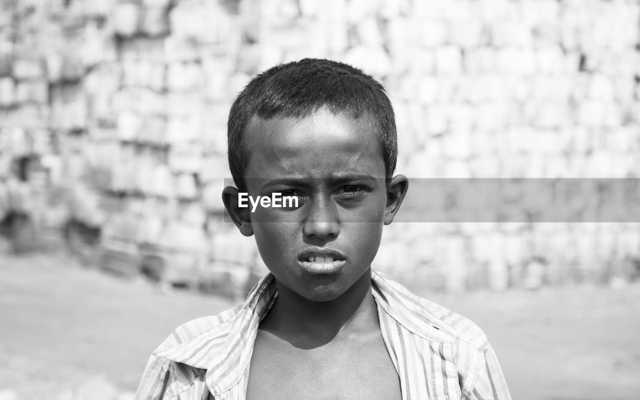 Portrait of poor boy standing on land