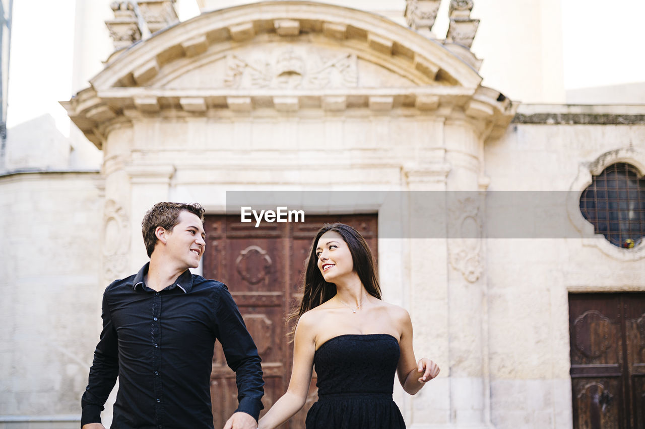 Couple walking against historic building