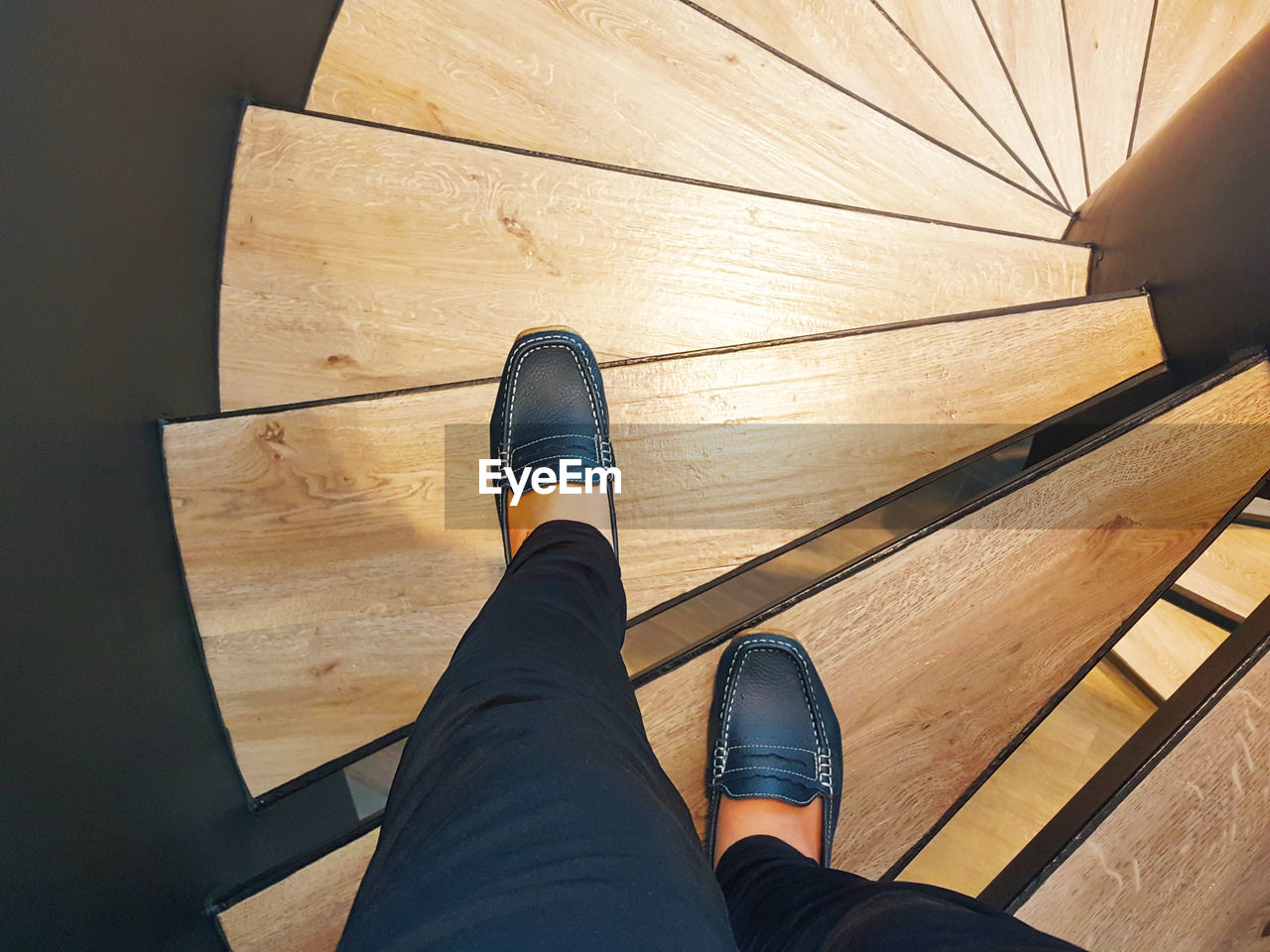 Low section of person on wooden spiral staircase