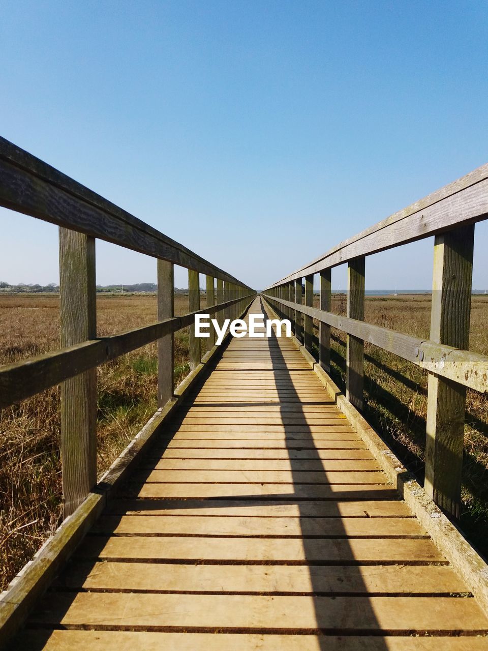 Footbridge amidst landscape against sky