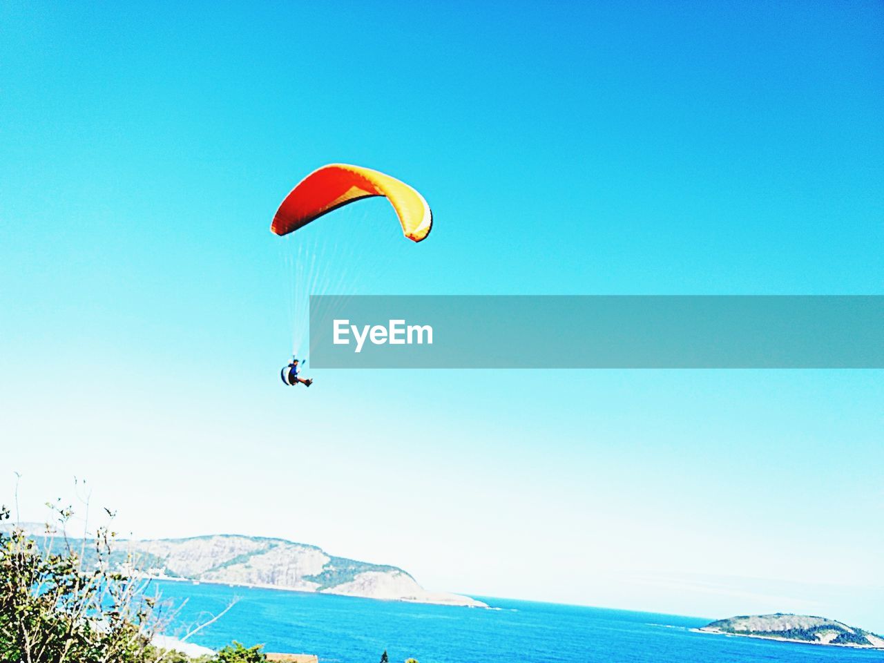 PERSON PARAGLIDING AGAINST BLUE SKY