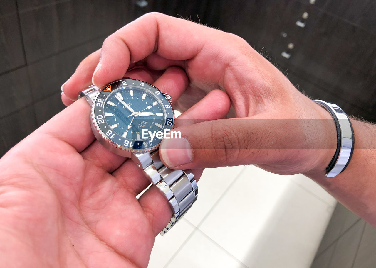 HIGH ANGLE VIEW OF PERSON HOLDING CLOCK