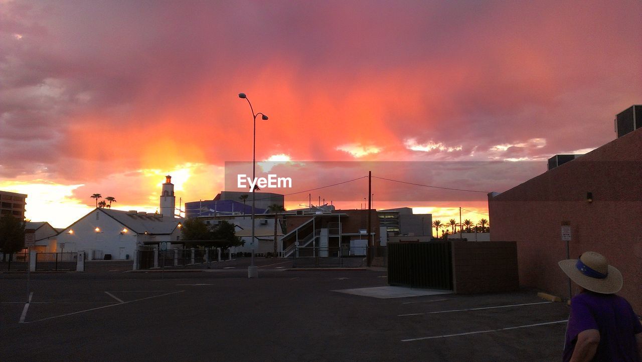 Street by buildings against cloudy sky during sunset