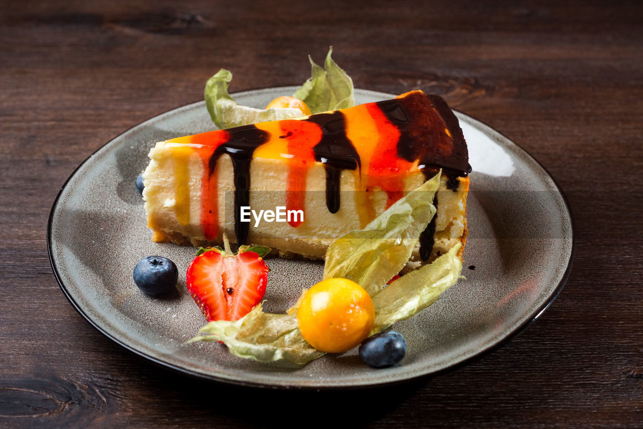 Delicate cheesecake with chocolate and strawberry syrup. piece of cake on a plate with fresh berries