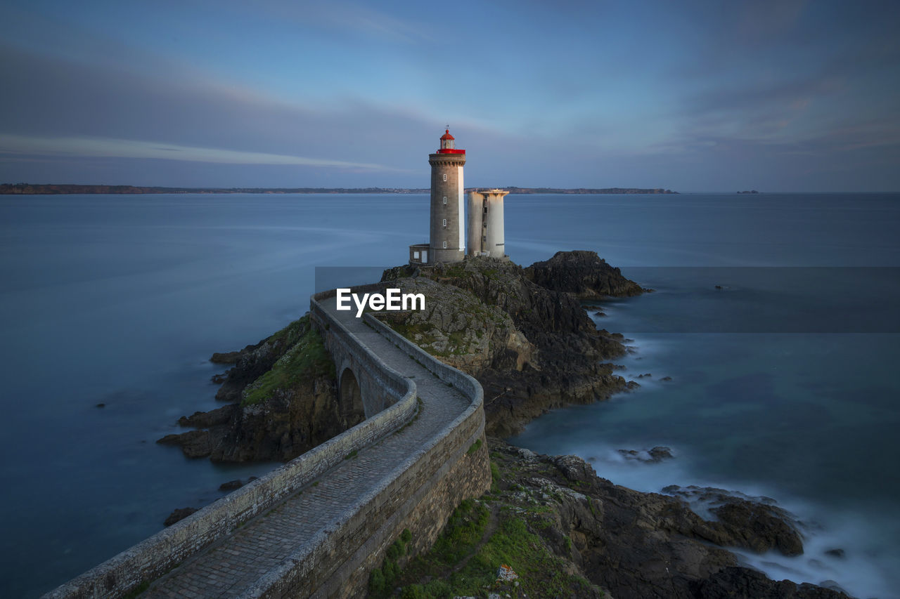 Lighthouse amidst sea against sky