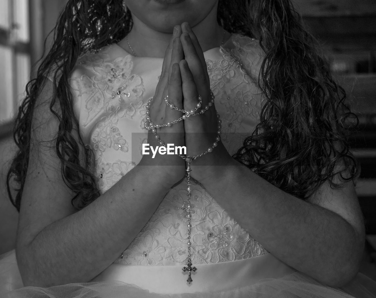 Midsection of girl holding rosary while praying