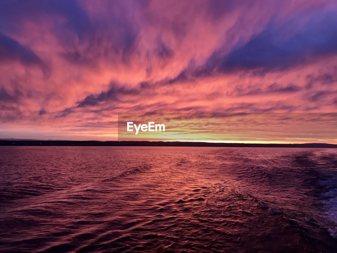Scenic view of sea against dramatic sky during sunset